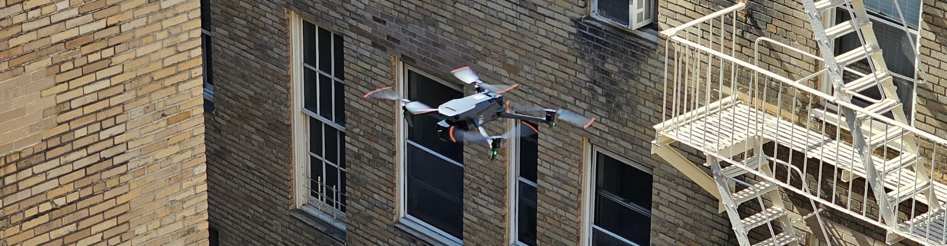 Inspection drone flying alongside a New York City brick facade