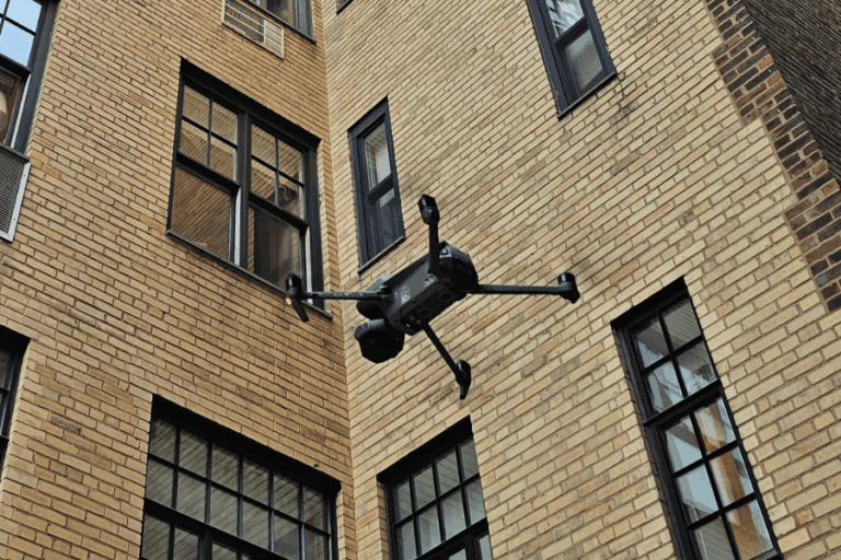 Drone performing close-range façade inspection of a brick residential building in New York City